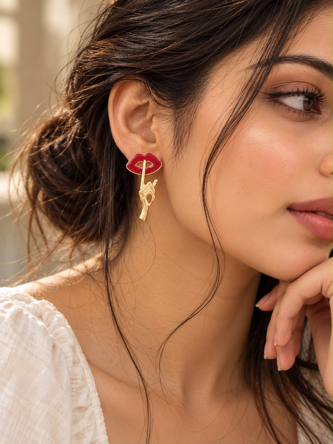 Model wearing Ju-el Mwah Earrings with playful red lips and gold-plated hand motif