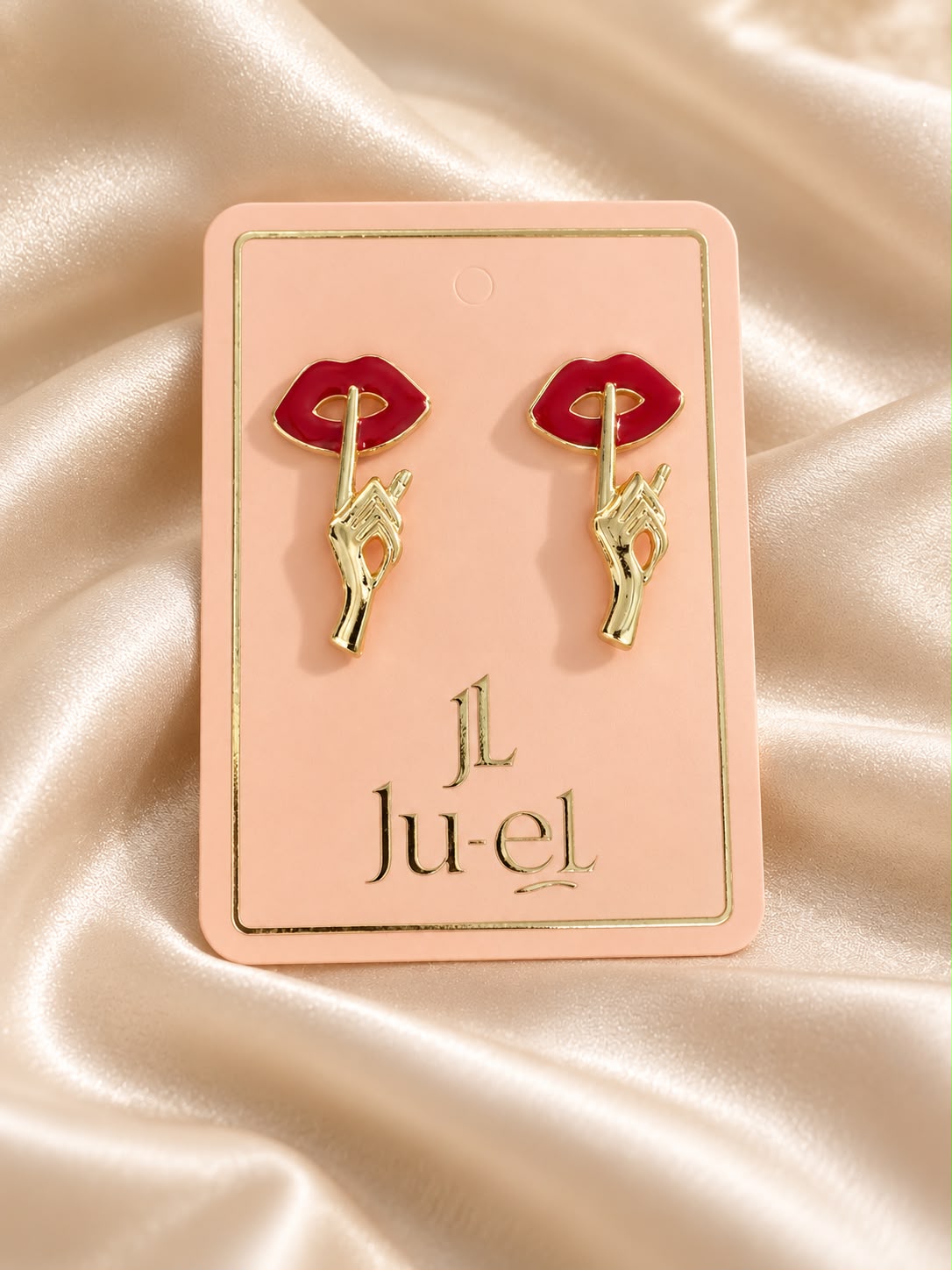 Ju-el Mwah Earrings featuring gold-plated alloy hand and red lips stud design on display card